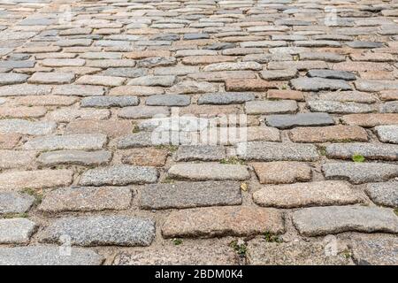 Eine alte Kopfsteinpflasterstraße an der Lower East Side von Manhattan. Reihen von Pflastern bilden ein unebenes Muster. Schöner Hintergrund oder Tapete. Stockfoto