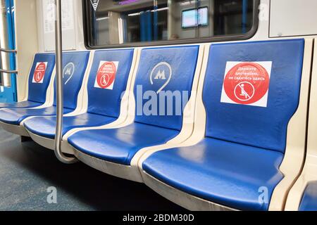 Moskau - 8. April 2020: Warnschild auf Sitzen in der U-Bahn wegen Coronavirus. Übersetzung: Halten Sie Abstand, sitzen Sie hier nicht. Soziale Distanzierung Stockfoto