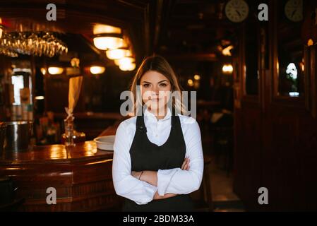 Portrait der jungen attraktiven kaukasischen blonden Kellnerin am Café Eingang Stockfoto