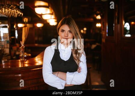 Portrait der jungen attraktiven kaukasischen blonden Kellnerin am Café Eingang Stockfoto