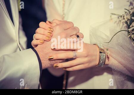 Die Hand des Bräutigams, die Hände des Paares mit den Trauringen. Schild, Symbol für Familienkonzept Stockfoto