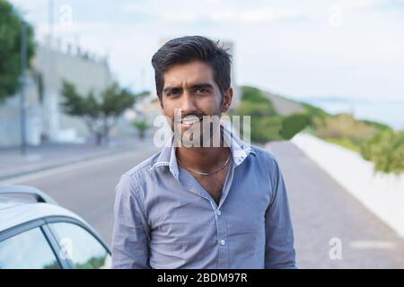 Glücklich lächelnder indischer Mann im Freien neben seinem Auto Stockfoto