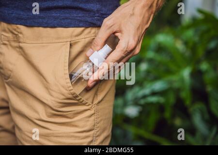 Der Mann hat ein Händedesinfektionsgel in seine Hosentasche gelegt, wenn er während der Corovid-Ausbruch-Krise um 19 Uhr nach draußen gehen wird, um die persönliche Gesundheit zu kümmern Stockfoto