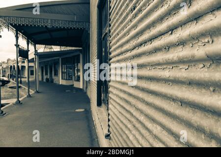 Clunes Australia - 15. März 2020; alte Gebäude entlang der Stadtstraße mit Wellblechaußenwand in Sepiafarben. Stockfoto
