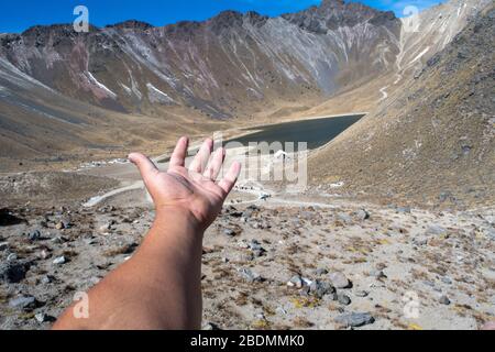 Hand zeigt einen See und ein Gebirge auf dem Gipfel des Nevado de Toluca, Mexiko Stockfoto