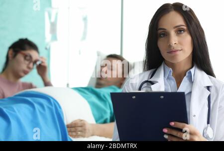 Doktor mit Mappe steht in Palette Kranker Mann Stockfoto