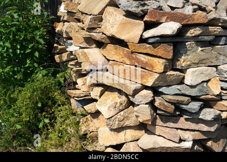 Stein natürliche Steinplatte in einem Haufen gestapelt. Naturstein-Steinplatte, in unebenen Reihen gelegt. Hintergrund der Steinplatte Stockfoto