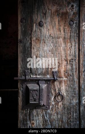 Alte rostige Stahlschloß-Schraube mit einem Schlüsselloch, das auf einer alten hölzernen Tür vom Mittelalter angebracht wird Stockfoto