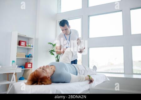 Ernster junger Therapeut, der mit seinem Patienten arbeitet Stockfoto