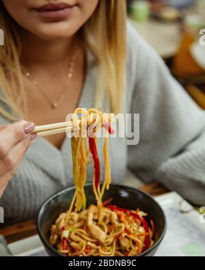 Frau, die Hühnernudel mit Essstäbchen isst Stockfoto