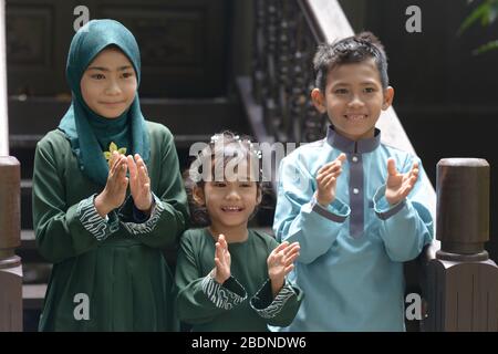 Muslimische Kinder klatschen die Hände, Hari Raya Eid Al-Fitr-Konzept. Stockfoto