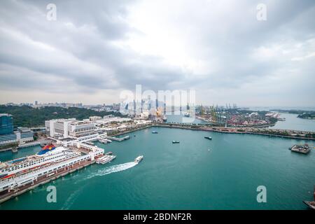 Seehafen in Singapur mit großem Kreuzfahrtschiff, Booten und Kranen im Hintergrund Stockfoto