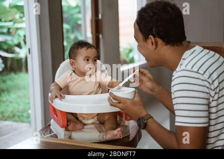 Vater füttert Baby. Mann zum Essen, der sich um seine Tochter kümmert Stockfoto