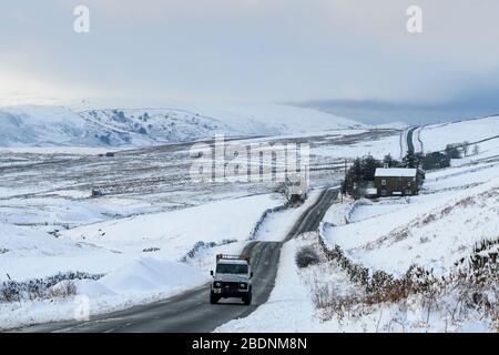 Verschneite Winterlandschaft (Land Rover Defender Fahren, Landstraße, Hochland Hügel, schneebedeckte Felder) - in der Nähe von Greenhow, Yorkshire Dales England Großbritannien Stockfoto