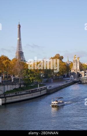 Blick auf die seine mit Boot, Eiffelturm und Alexander-III-Brücke an einem sonnigen Herbsttag in Paris Stockfoto