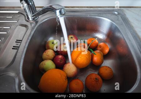 Orangenapfel und Mandarine in der Küchenspüle Stockfoto