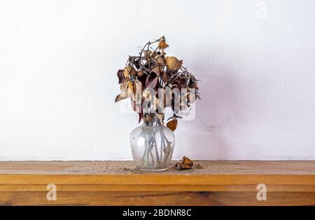 Glasvase auf Kamin sitzend mit toten getrockneten Schnittblumen Stockfoto