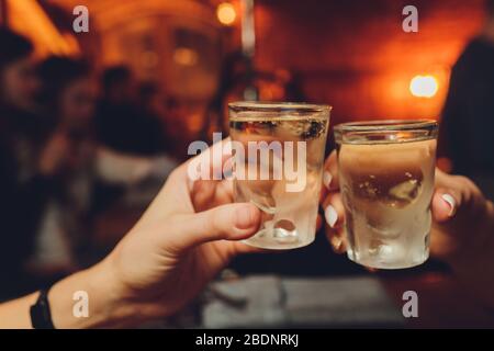 Nahaufnahme von Mädchen, die Cocktails im Nachtclub trinken. Mädchen haben gute Zeit, jubeln und trinken kalte Cocktails, genießen Freundschaft zusammen in der Bar, c Stockfoto