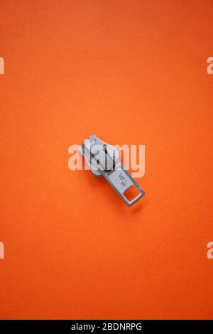 Metallic-Reißverschluss auf dem orangefarbenen Hintergrund Stockfoto