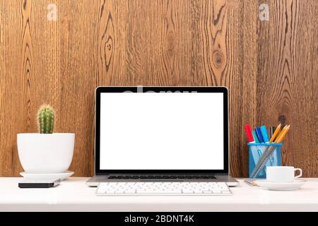 Arbeitsplatz mit Laptop-Computer weiß leeren Bildschirm auf Arbeitstisch Vorderansicht, moderne Gadgets. Laptop auf einem Tisch über Holzwand. Stockfoto