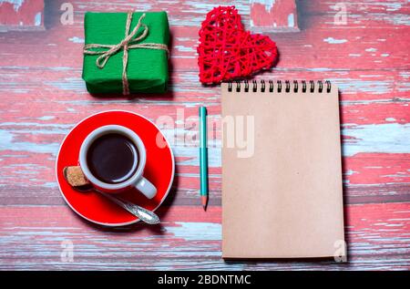 Notizblock, Tasse Kaffee, Schachtel mit Geschenk auf einem blauen Holztisch. Platz für Text, Draufsicht Stockfoto