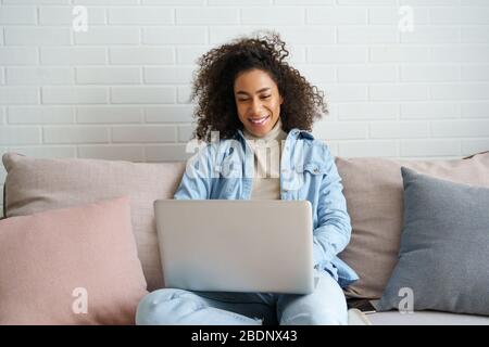 Glücklich afrikanischen Teenager-Mädchen mit Laptop-Computer auf Sofa sitzen. Stockfoto