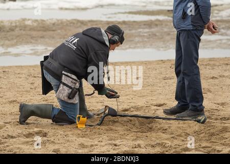 Wladiwostok, Russland - 26. März 2020: Ein Mann mit Metalldetektor sucht einen Schatz im Sand. Stockfoto