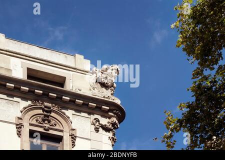 Nahaufnahme einer Skulptur auf dem Dach eines historischen, traditionellen, alten Gebäudes in Barcelona mit klarem blauen Himmel. Es ist ein sonniger Sommertag. Stockfoto