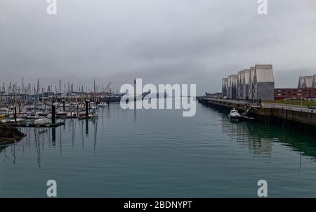 Die Marina und das vertäute Pilotboot des Hafens von Dunkirk mit dem Breakwater und Leuchtturm im Hintergrund. Stockfoto