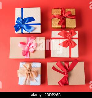 Flat legte ein Set festlicher Weihnachtsgeschenkboxen auf rotem Hintergrund. Stockfoto