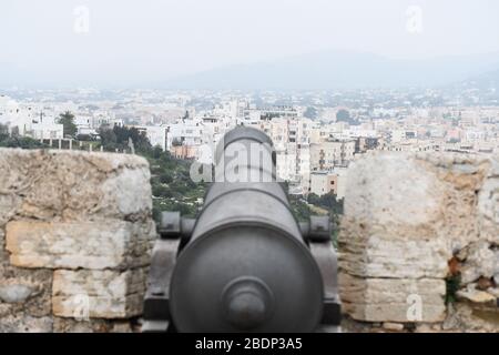 Schwarze Kriegskanone, die von einem alten Schloss auf ibiza auf eine Stadt zeigt Stockfoto