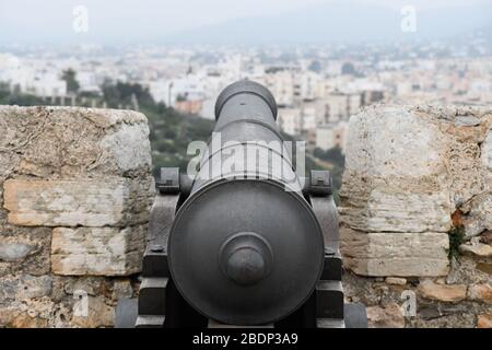 Schwarze Kriegskanone, die von einem alten Schloss auf ibiza auf eine Stadt zeigt Stockfoto