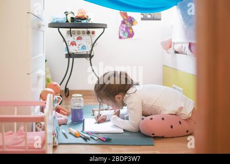 Mädchen malen und schreiben, die zu Hause Hausaufgaben machen, während der Selbstisolation der Kovid 19. Home Education Konzept mit leerem Kopierraum für Editor-Text. Stockfoto