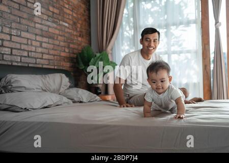 Stolzer Vater, der sein Baby ansieht und zu kriechen beginnt Stockfoto