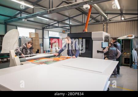 Eine große Gruppe von Mitarbeitern, die der Bediener des Druckerherstellers ist, arbeitet in der digitalen Druckmaschinenhalle und im Druckereibüro mit vielen verschiedenen Maschinentypen Stockfoto