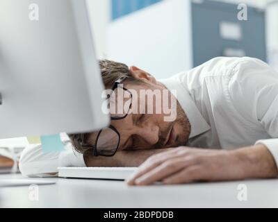 Erschöpfter, müde Business Executive schläft auf seinem Schreibtisch, Stress und Überarbeitkonzept Stockfoto