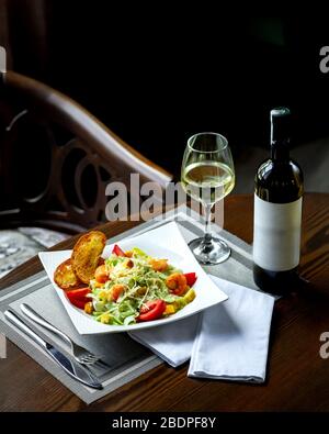caesar Salat mit Rimps und einem Glas Wein Stockfoto