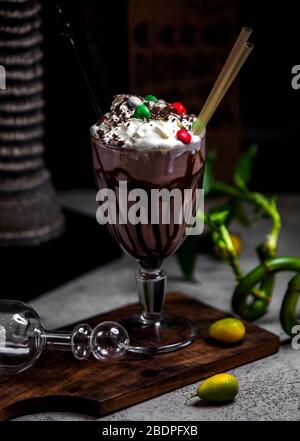 Schokoladenmilchshake mit Schlagsahne und Bonbons darauf Stockfoto