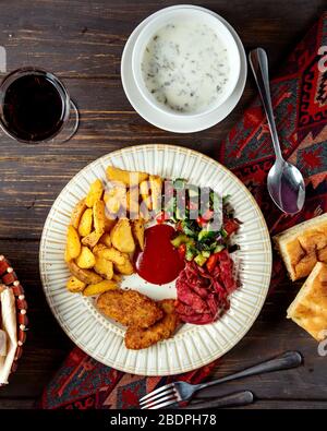 Gebratene Koteletts und Kartoffeln mit Hirtensalat und Dovga Stockfoto