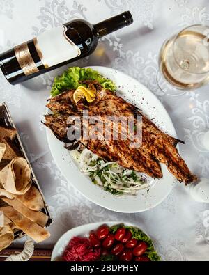 Gebratener Fisch und eine Flasche Wein Stockfoto