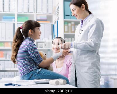 Doktor, der das verletzte Handgelenk eines Mädchens mit Gaze und Binde, erster Hilfe und Gesundheitskonzept umwickelt Stockfoto