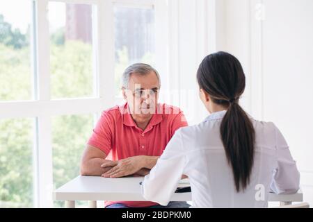 Ältere Patienten hören junge Ärztin in einem Krankenhaus Stockfoto