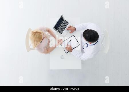Der männliche Arzt berät junge Patienten. Draufsicht Stockfoto
