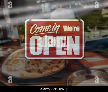 Ein Geschäftsschild, das auf dem Fenster des Pizzabadens „Come in We're Open“ steht. Stockfoto