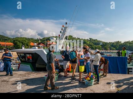 Horizontaler Blick auf Passagiere, die mit einer Fähre am Hafen von Padang Bai in Bali, Indonesien, einsteigen. Stockfoto