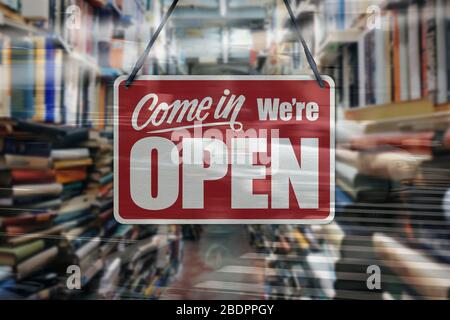 Ein Geschäftszeichen, das auf einem Buchladen-Fenster „Come in We're Open“ steht. Stockfoto