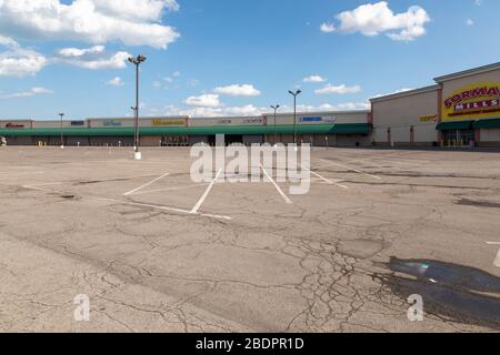 Detroit, Michigan, USA. April 2020. Der Parkplatz ist völlig leer und die Geschäfte sind an einem Strip Mall an der Ostküste Detroits geschlossen. Michigan Reg. Gretchen Whitmer hat angeordnet, dass nicht essentielle Unternehmen während der Coronavirus-Krise geschlossen werden. Kredit: Jim West/Alamy Live News Stockfoto