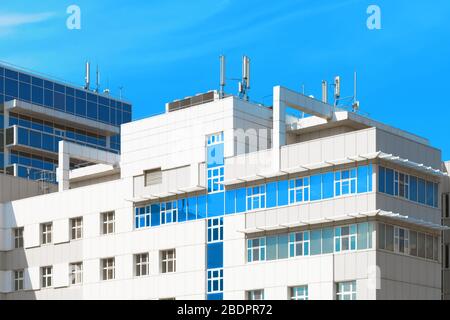 Modernes Krankenhausgebäude mit blauen kreuzförmigen Fenstern gegen blauen Himmel Stockfoto