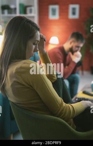 Junges Paar nach einem Heimkampf: Sie sind traurig, sitzend und denkend, Beziehungsprobleme Konzept Stockfoto