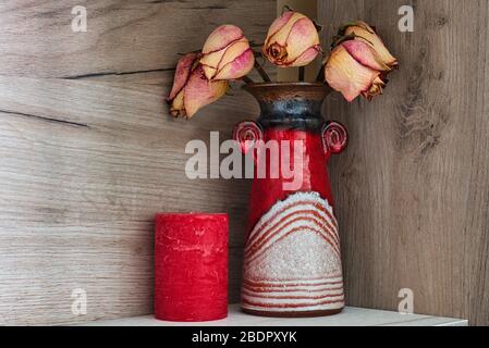 Rote Vase und Kerze Natur morte Bild in Pastellfarben, trockene Rosen Stockfoto